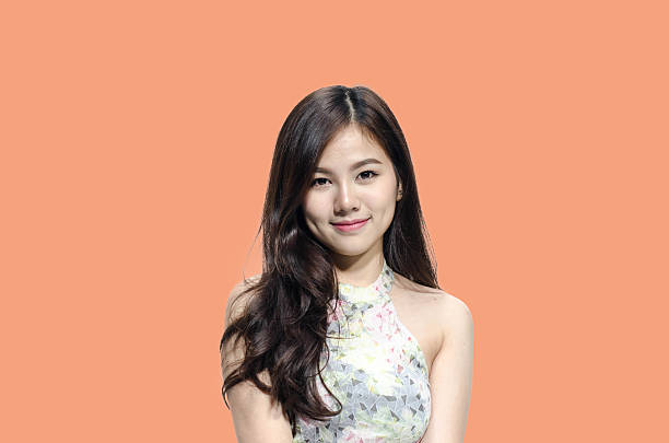 Asian woman smiling with dimple long hair black eyes on orange background